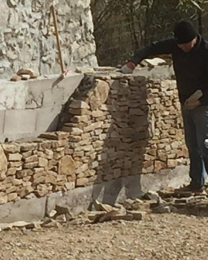 Un maçon de l'équipe monte un mur en pierres sèches sur un chantier à Marseille