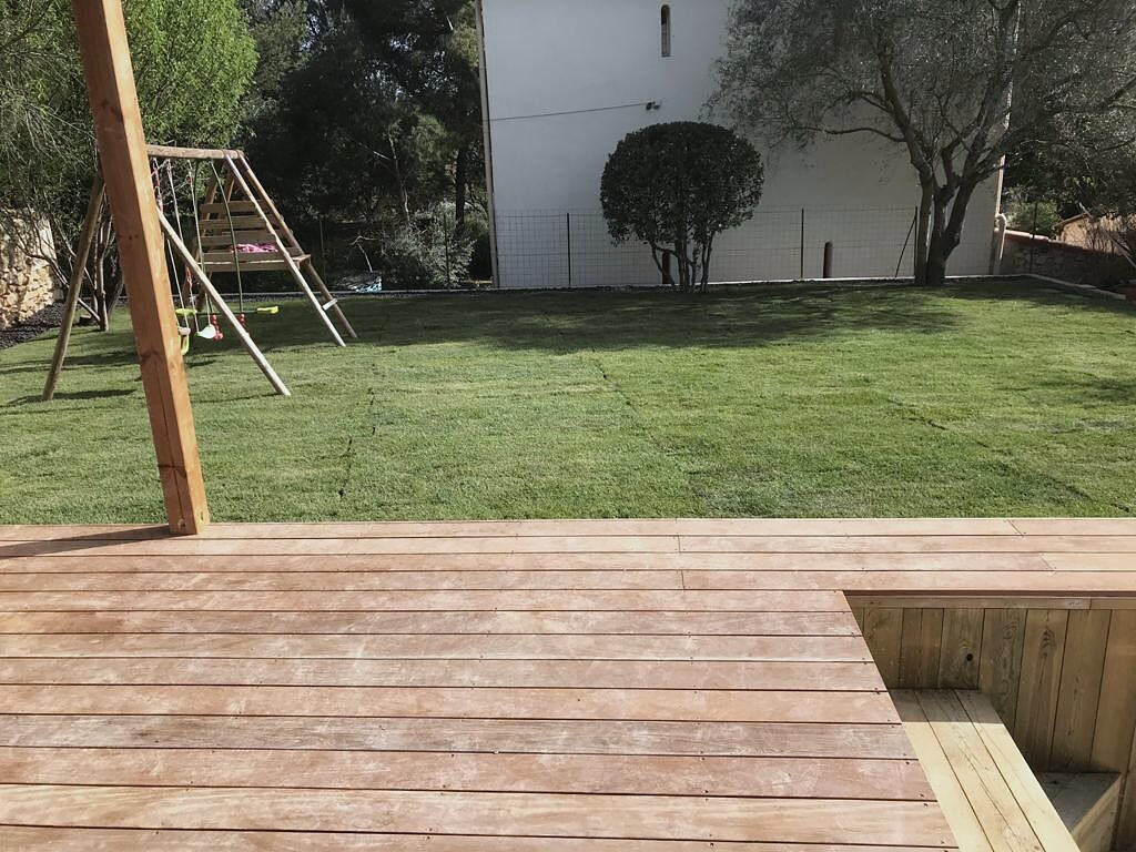 Le même terrain engazonné, avec terrasse en bois et portique de jeux