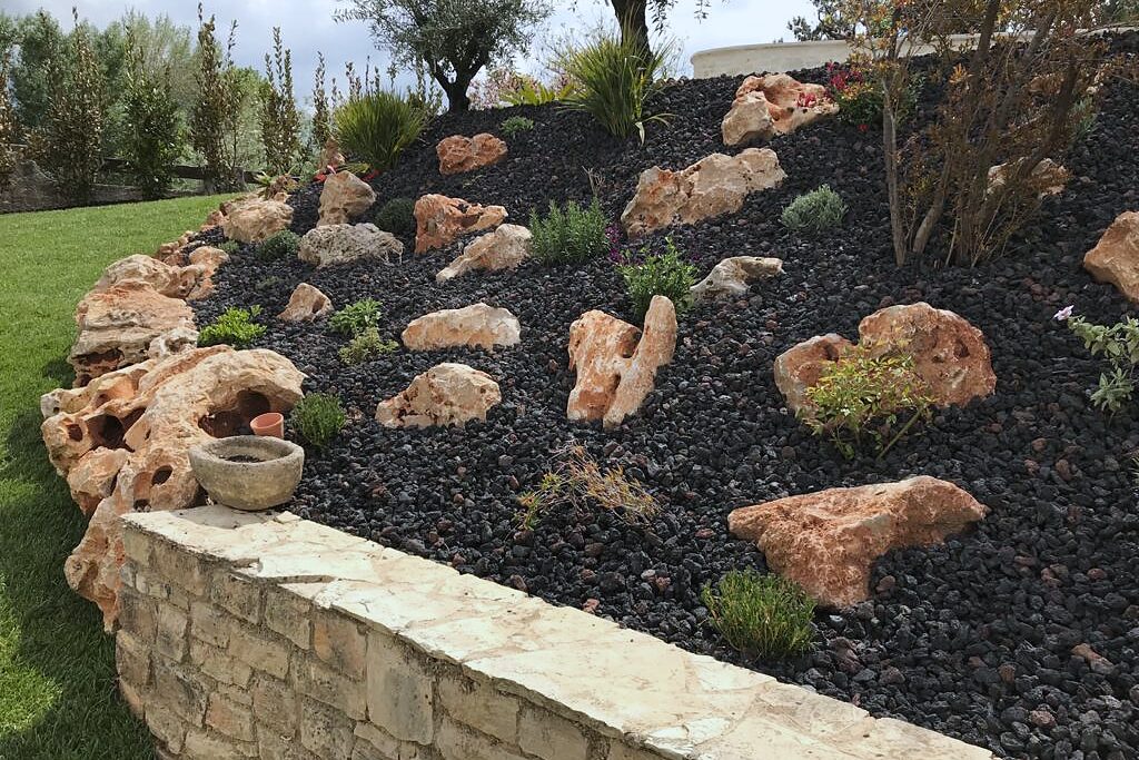 Muret en pierres et massif de galets planté de rochers