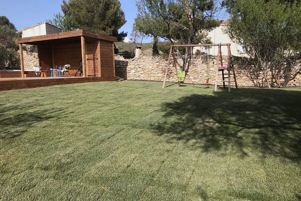 Jardin familial engazonné avec pool house et portique en bois