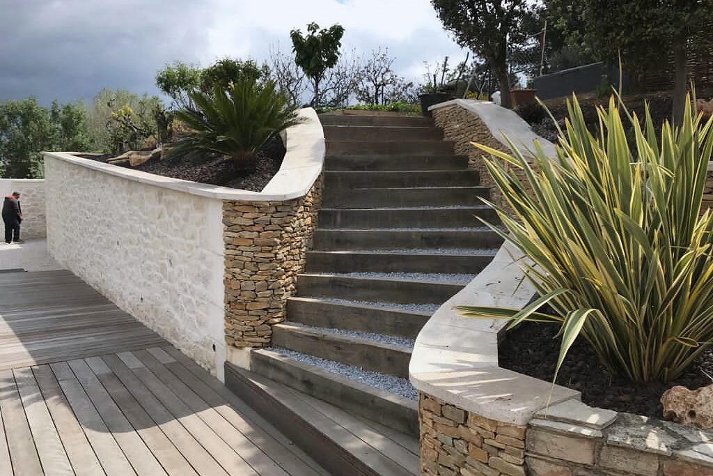 Escalier en pierres et terrasse en bois dans un jardin en pente