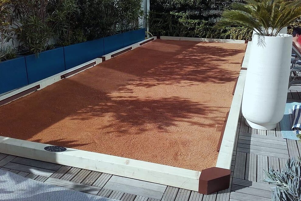 Terrain de boules en terre battue bordé d'une terrasse en bois