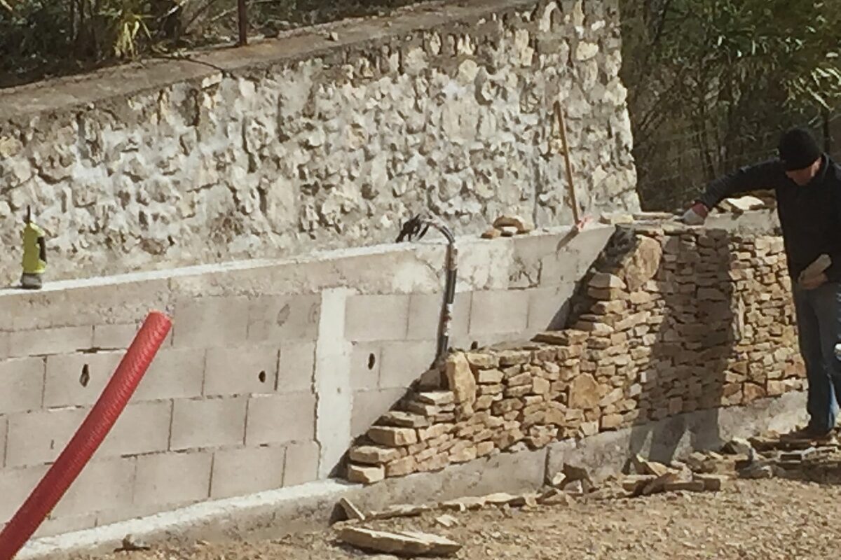 Maçon montant un mur en pierres sèches